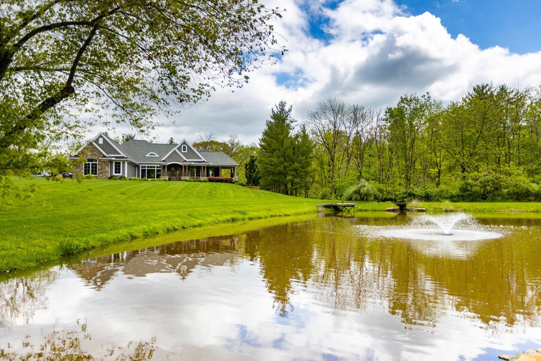 home looking out on a green lawn and pond