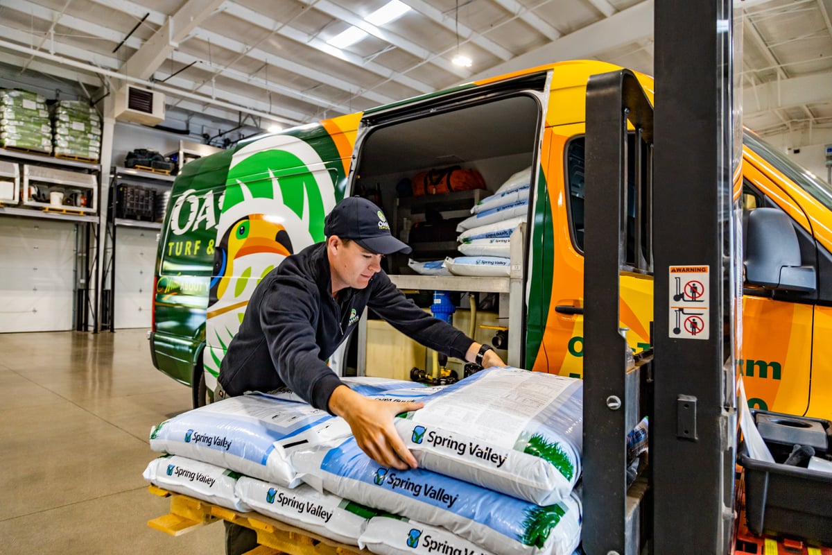 lawn care professional loads fertilizer into truck 