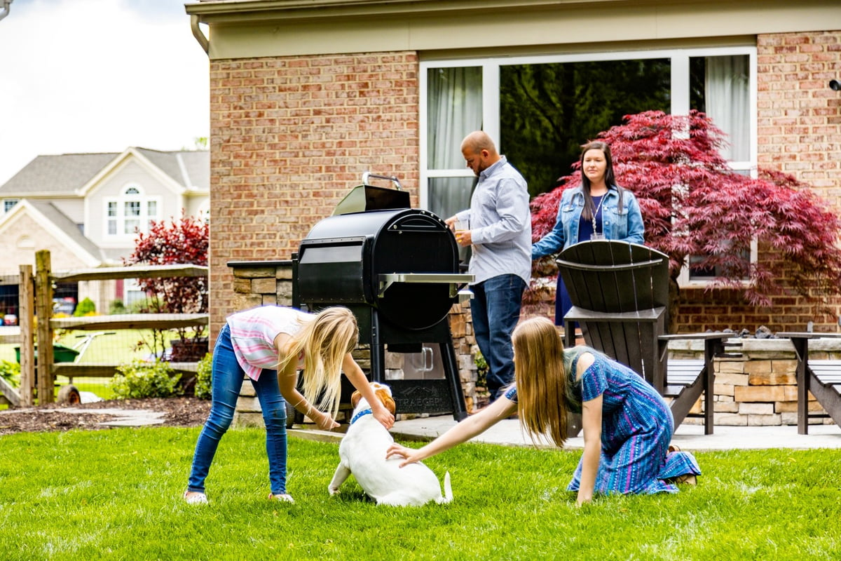 family plays in backyard on grass with dog