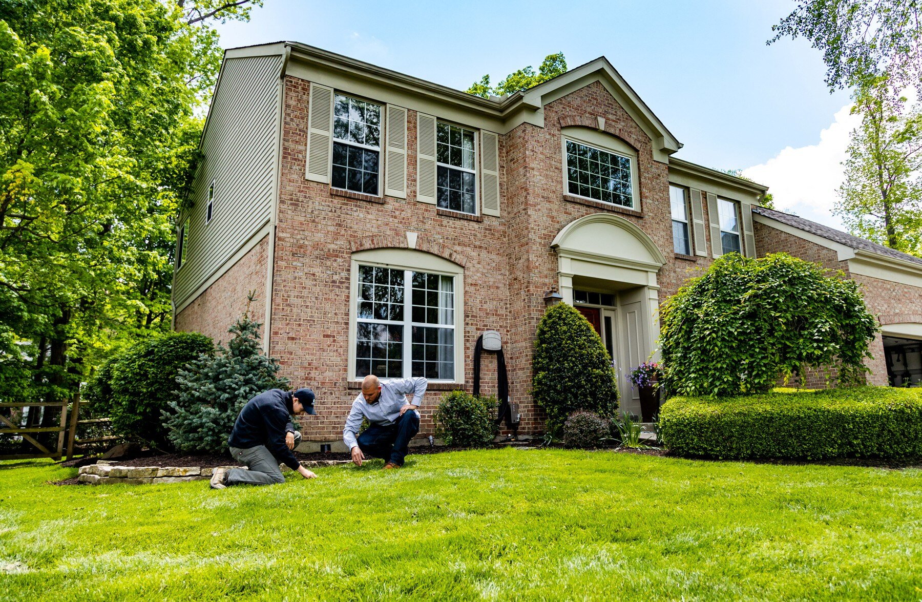 homeowner and lawn care expert inspect grass