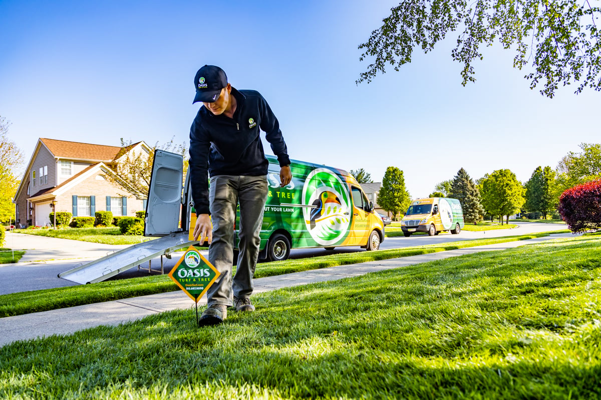 lawn care technician placing sign on green grass