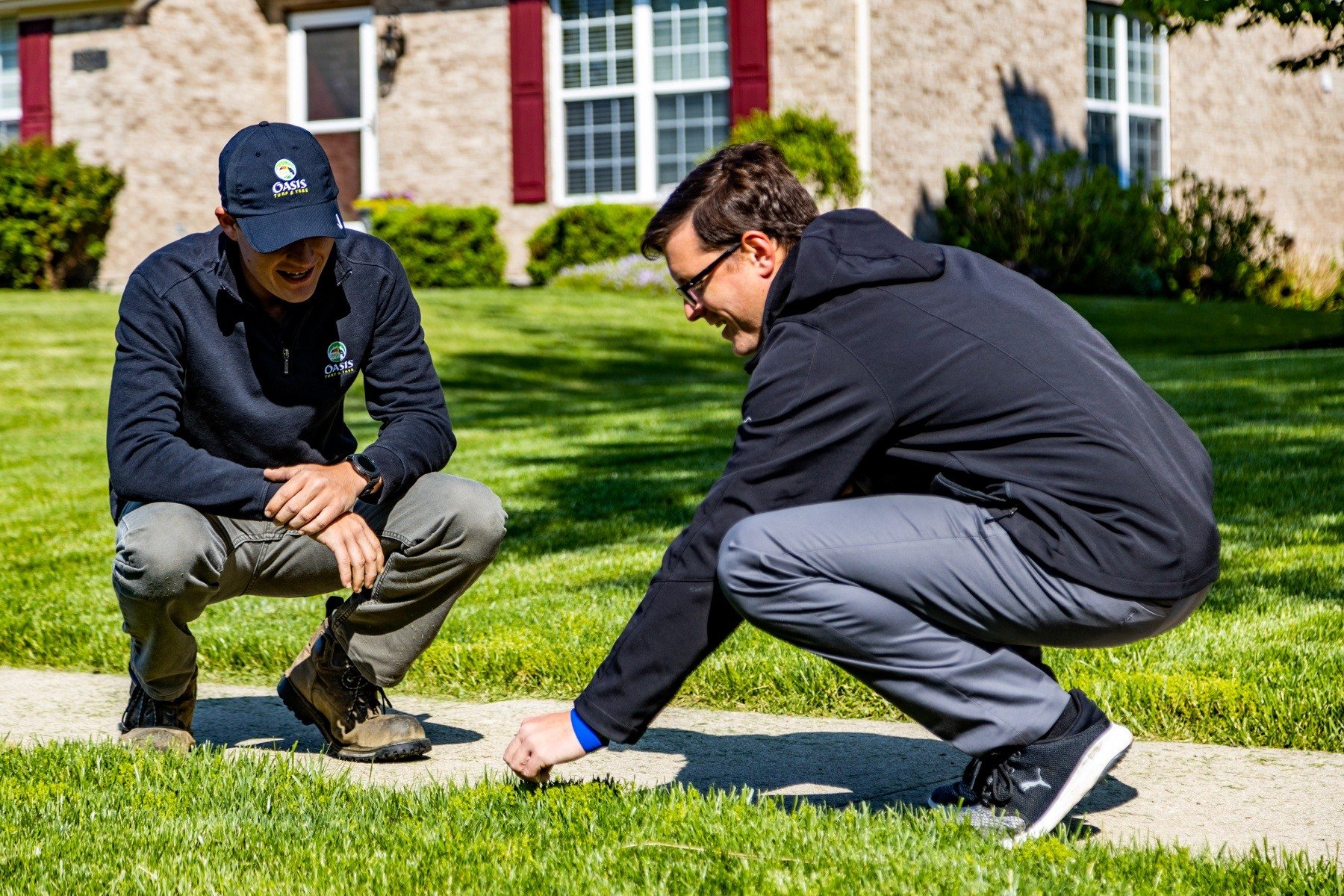 technician and customer inspect grass at home