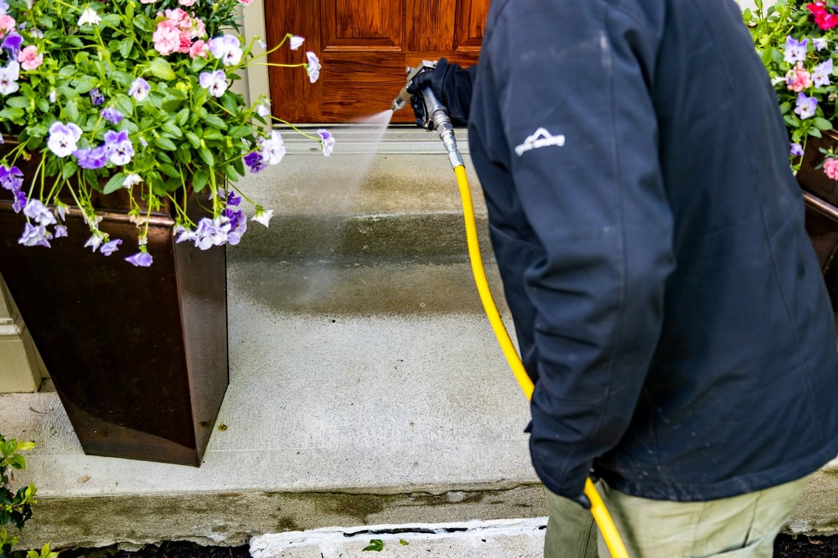 perimeter pest control technician spraying porch