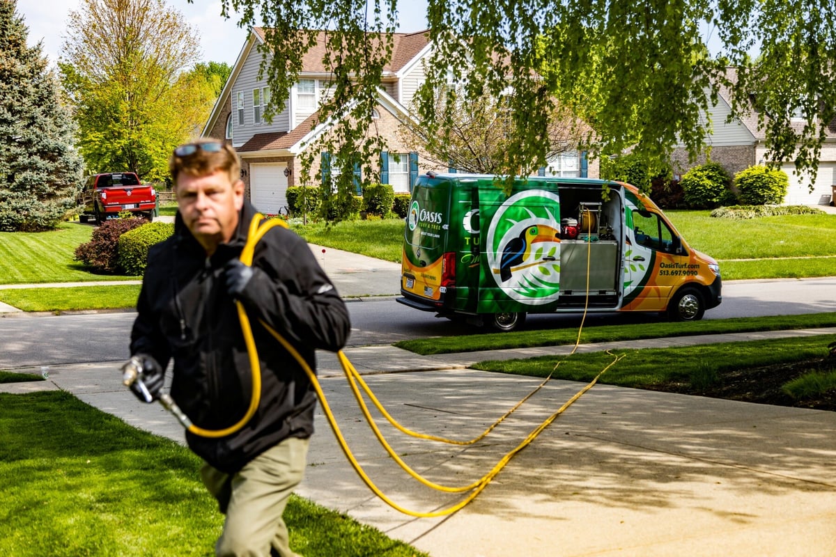 perimeter pest control technician pulling hose to spray