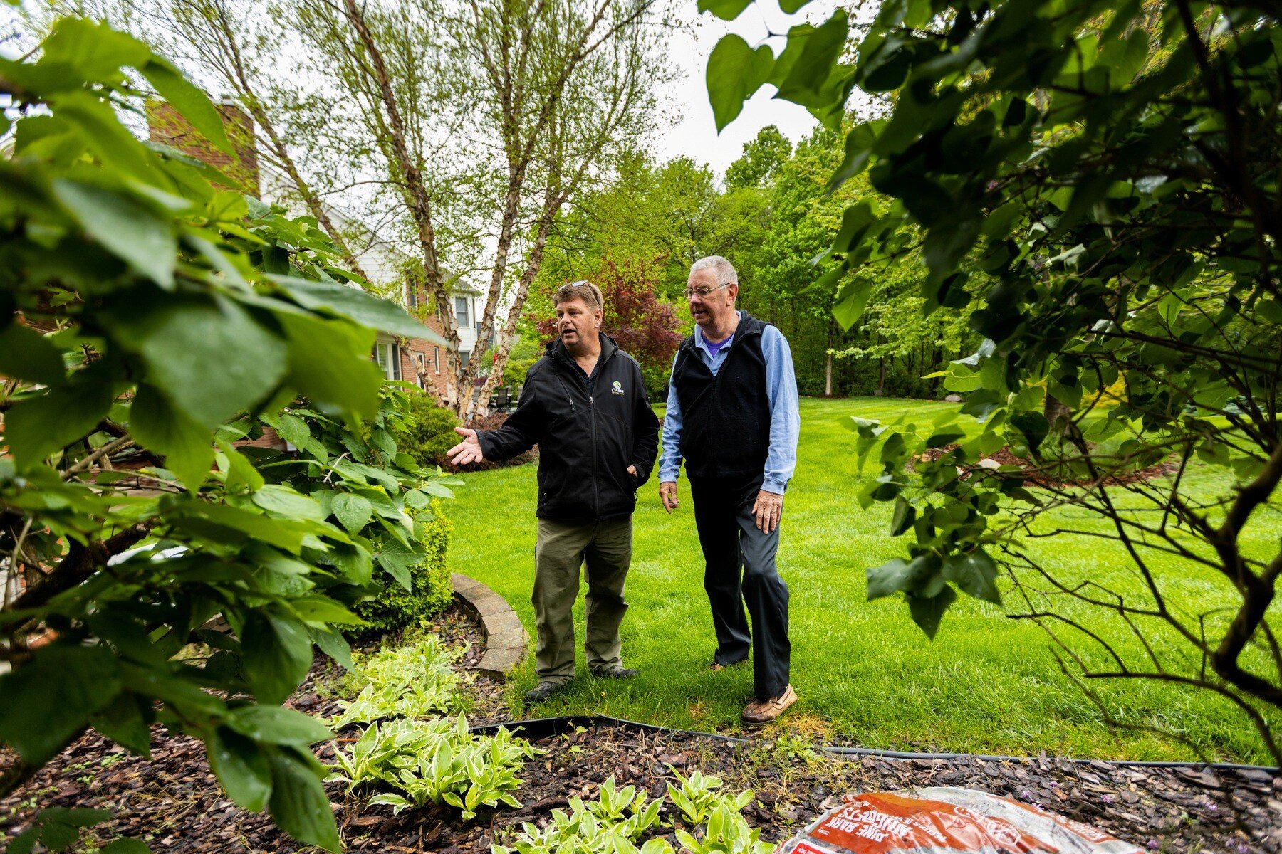 customer and plant health care technician inspect shrubs