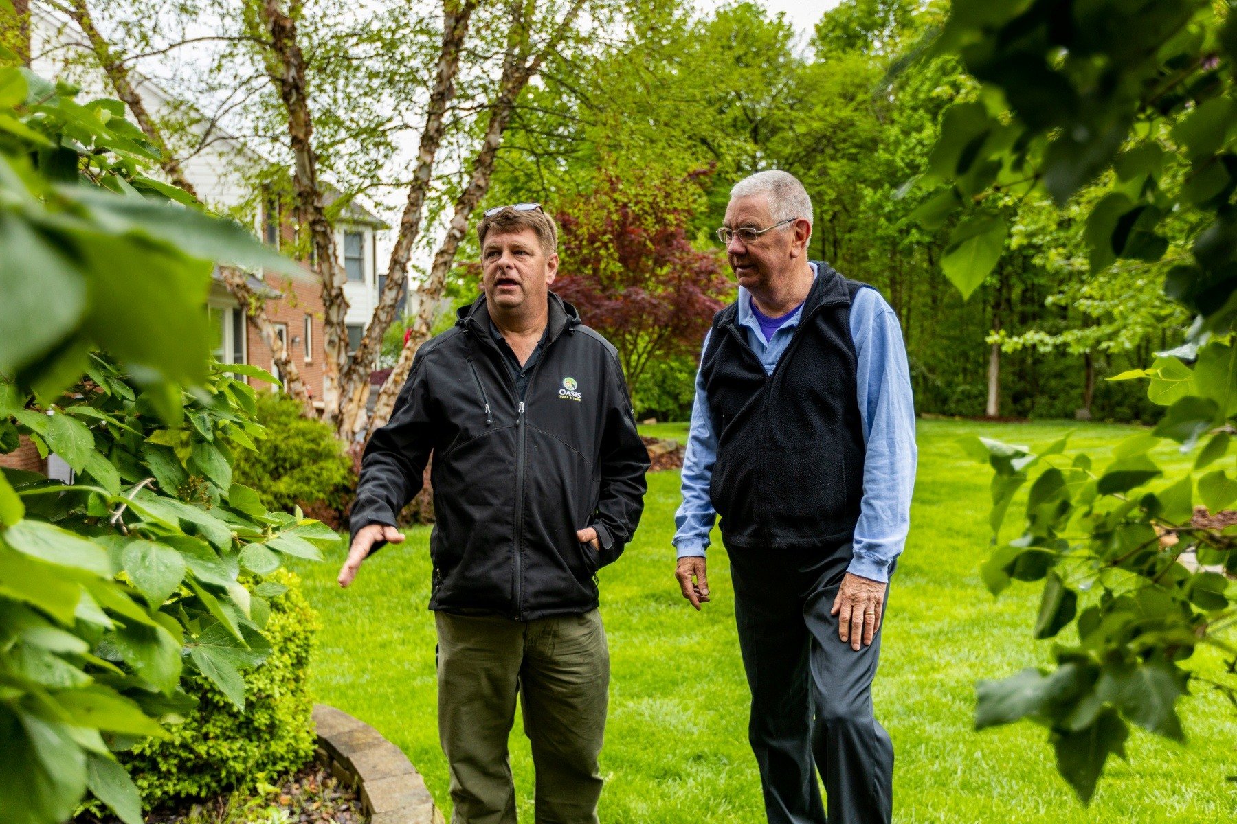 plant health care technician inspecting shrubs with customer 8