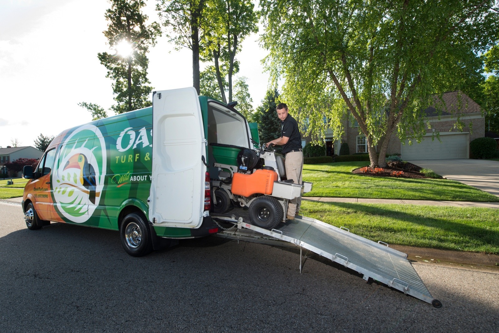 Oasis Lawn Care technician moving equipment from van