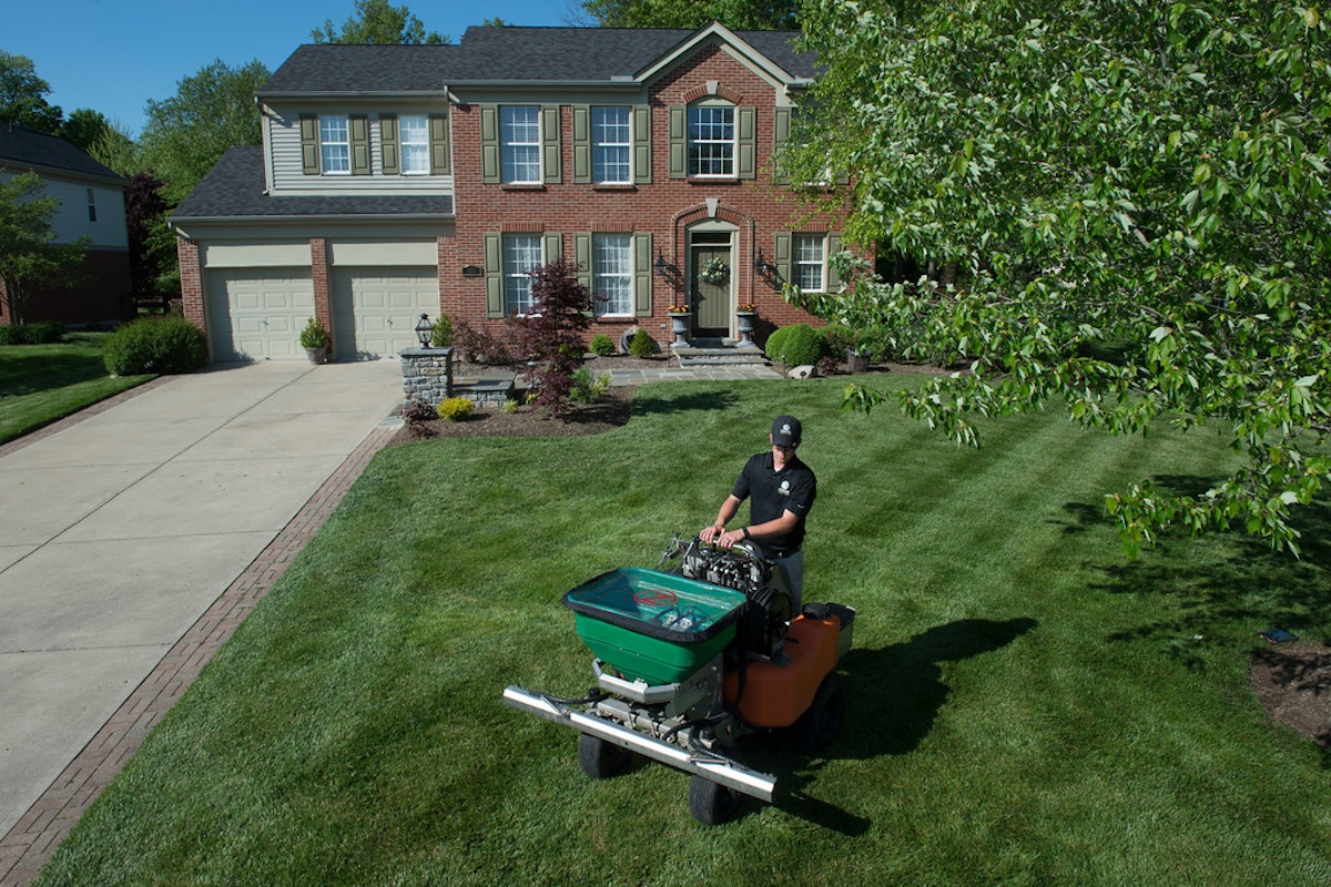 lawn care technician fertilizes lawn