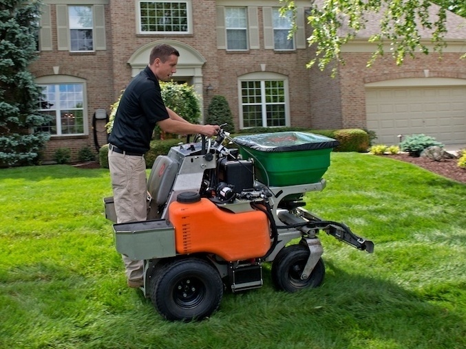 lawn care technician applies grub control