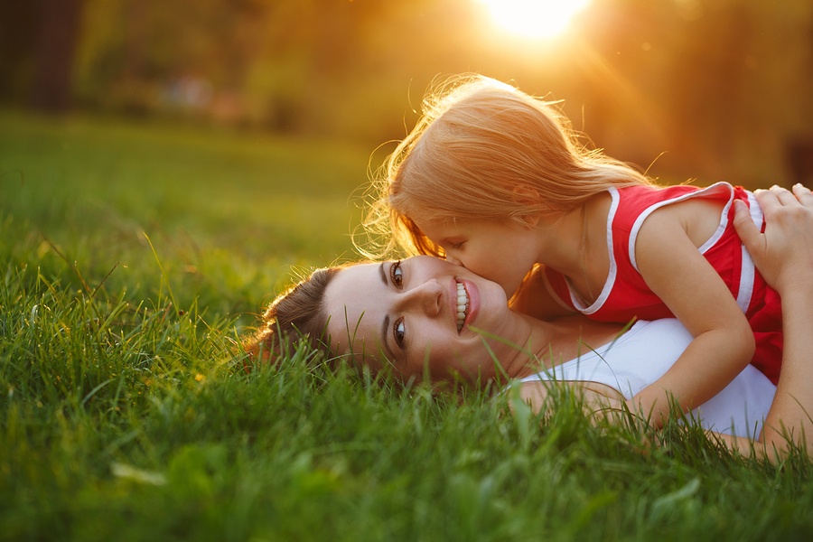 mom and child lay in safe healthy grass