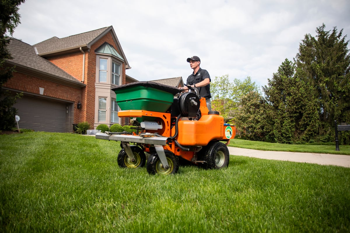 lawn care technician spreads granular fertilizer