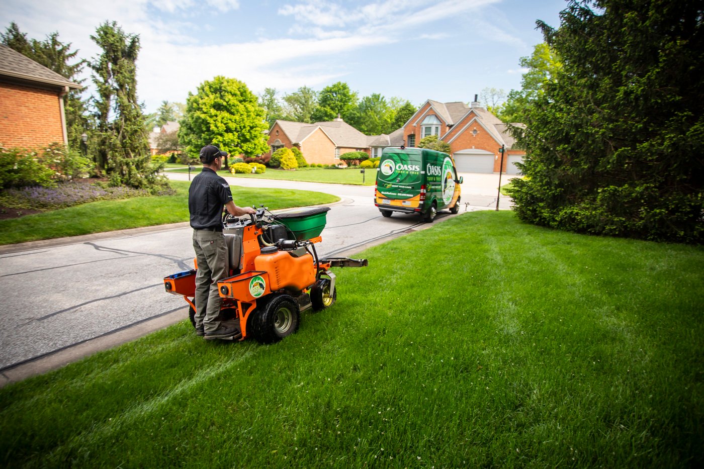 Oasis lawn care technician applying grub control