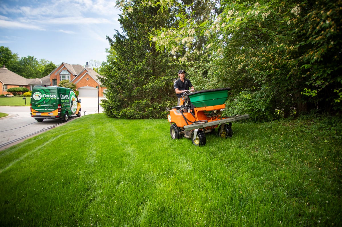 lawn care technician fertilizes lawn