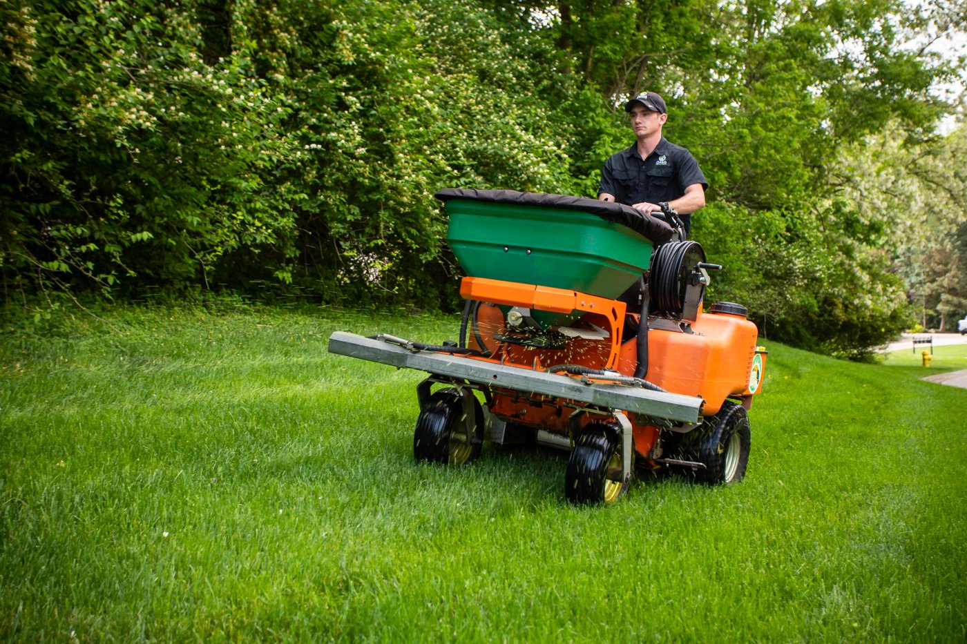 Oasis Lawn Care technician applying granular fertilizer with top-quality equipment