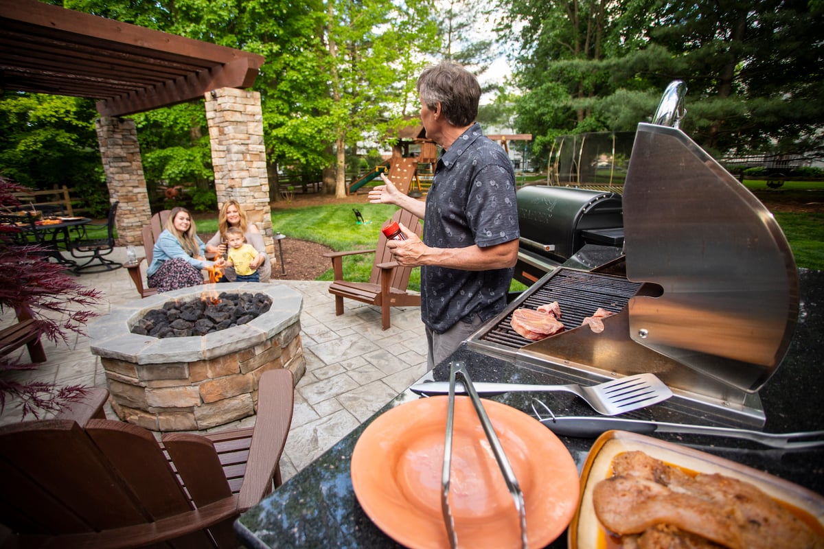 family sitting outside with grill patio and firepit