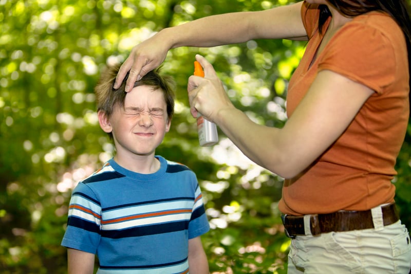 mother spraying child with bug spray